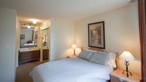 Une chambre d’hôtel avec un lit, deux lampes de chevet, une table de chevet, une commode, un miroir et un tableau encadré au mur.