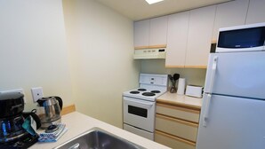 Une cuisine équipée d’une cuisinière, d’un four à micro-ondes, d’un réfrigérateur et d’une machine à café.
