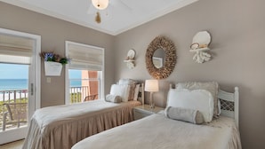 A bedroom with two beds, a ceiling fan, a decorative mirror, and a view of the ocean through a sliding door. - "Jen's Creole Cottage" Amazing Gulf Front Property! (Navarre Beach)