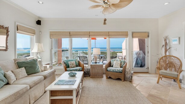 A spacious living room with a large window overlooking the sea, a ceiling fan, and wicker furniture. - "Jen's Creole Cottage" Amazing Gulf Front Property! (Navarre Beach)