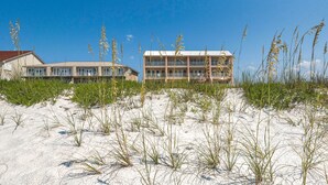 A beachfront hotel with a two-story structure, sandy beach in front, and tall grasses. - "Jen's Creole Cottage" Amazing Gulf Front Property! (Navarre Beach)