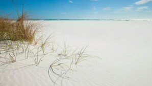 A beach with white sand and sparse vegetation. - "Jen's Creole Cottage" Amazing Gulf Front Property! (Navarre Beach)