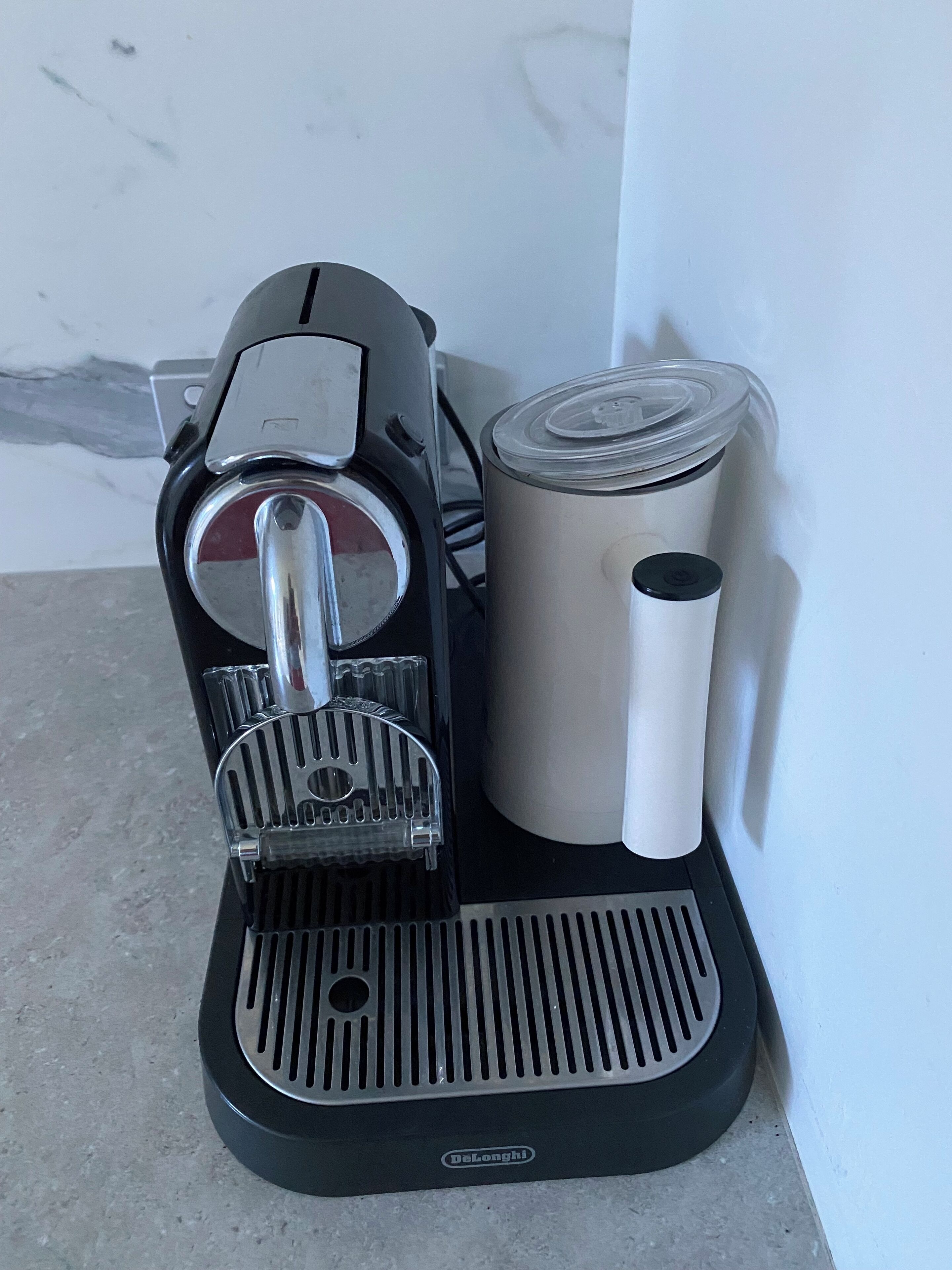 A DeLonghi espresso machine with a milk frother and a milk pitcher.