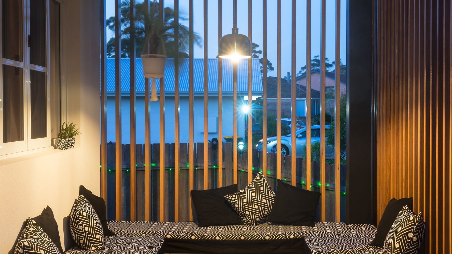 Un dormitorio con una cama, una ventana con persianas y vistas al exterior.