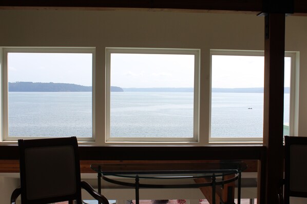 A room with three large windows offering a view of a calm body of water and a distant shoreline. - Olympic Peninsula, from Coast to Forest, Scenic Hiking, Kayaking, Fishing, GEM. (Brinnon)
