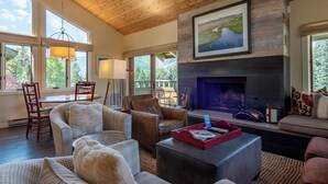 A cozy living room with a fireplace, comfortable seating, and large windows offering a view of the outdoors. - Wildflower Condo 655 - Third Floor Penthouse w/ Baldy Views & Sun Valley Pool (Sun Valley)