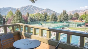 A balcony with a table and chairs, overlooking a tennis court and mountains. - Wildflower Condo 655 - Third Floor Penthouse w/ Baldy Views & Sun Valley Pool (Sun Valley)