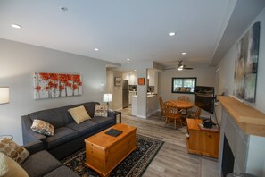 A modern living room with a sofa, coffee table, and a dining area with chairs and a table. - Stoney Creek Northstar 8 (Whistler)