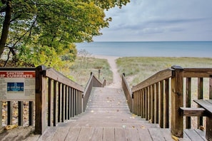 A wooden staircase leading to a beach with a caution sign about rip currents.