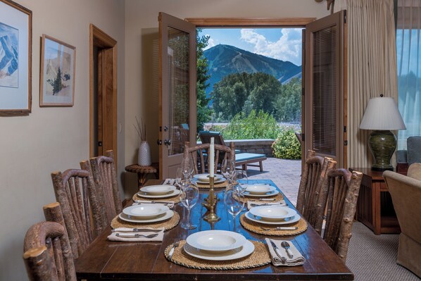 A dining table set for six with a mountain view through an open door. - Captivating Historic Cottage with Fireplace (Sun Valley)