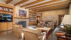 A cozy living room with a fireplace, bookshelves, a television, and comfortable seating. - Captivating Historic Cottage with Fireplace (Sun Valley)