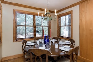 Une salle à manger avec une table en bois dressée pour quatre personnes, entourée de chaises.