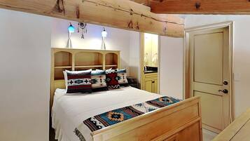 Un dormitorio con cabecera de madera, una cama con ropa de cama estampada, una mesita de noche y un armario.
