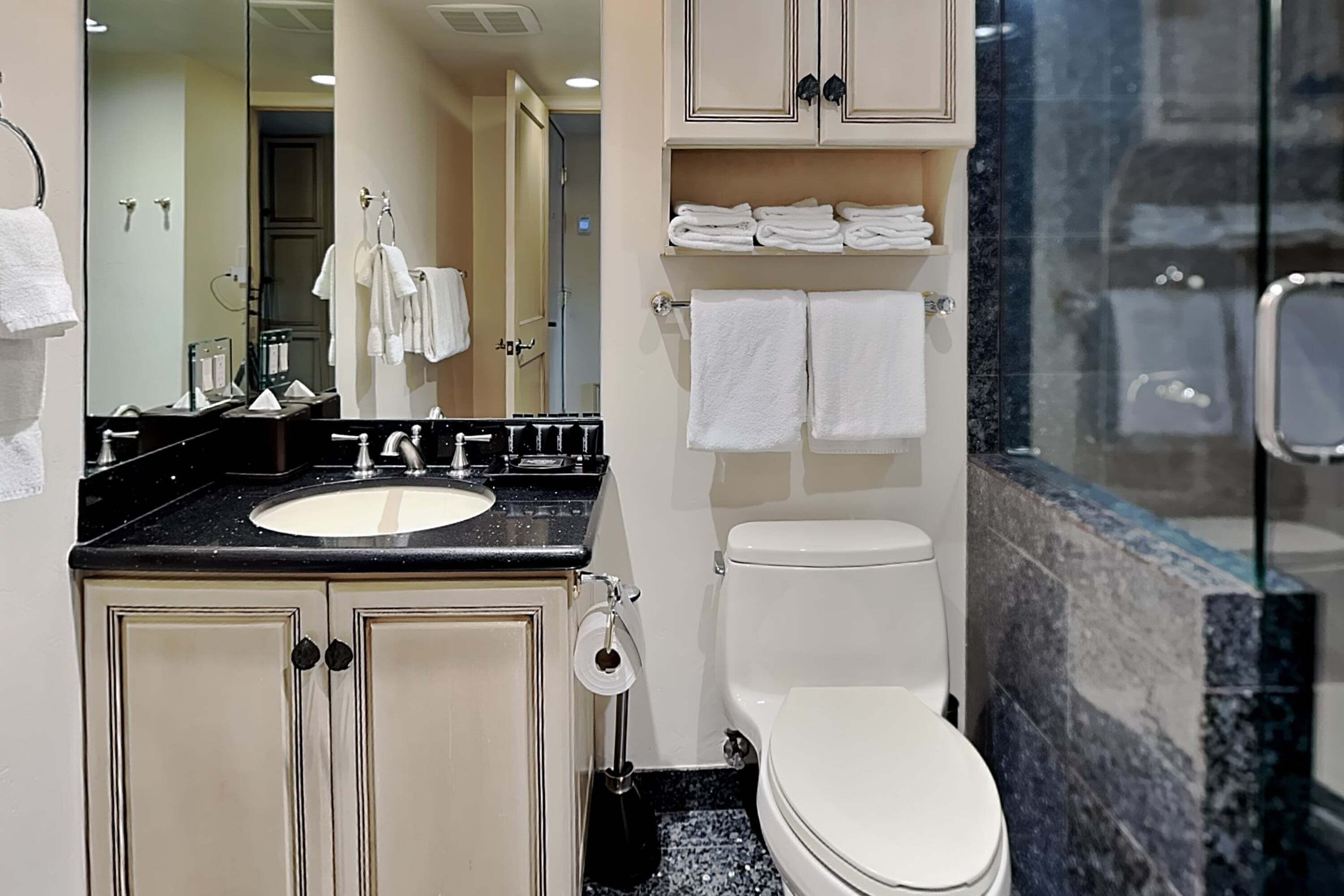 A bathroom with a sink, toilet, and a glass shower enclosure.