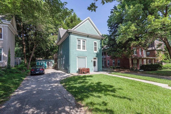 A two-story house with a front porch, a driveway, and a car parked in front.