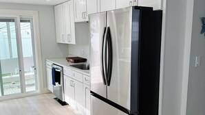 A modern kitchen with white cabinets, a stainless steel refrigerator, and a built-in oven. -  LOCATION! COMPLETE REHAB Great pool, close to north bean pt., twin family rooms (Anna Maria)