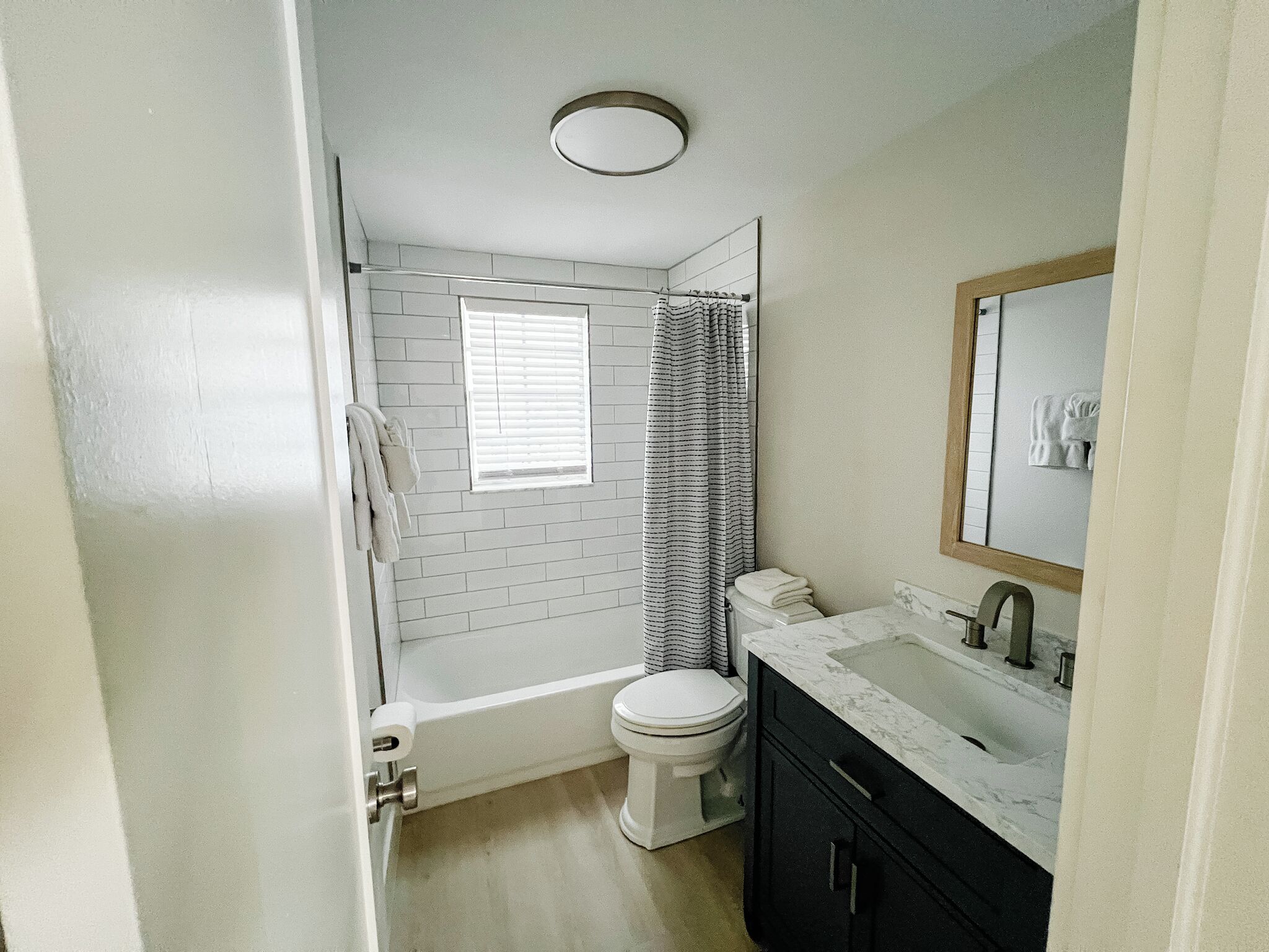 Une salle de bain avec des toilettes blanches, une baignoire, un rideau de douche et un meuble-lavabo avec un miroir.