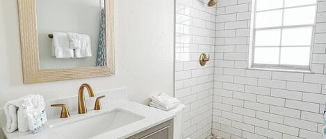 Un baño con lavamanos, tocador y inodoro blancos.