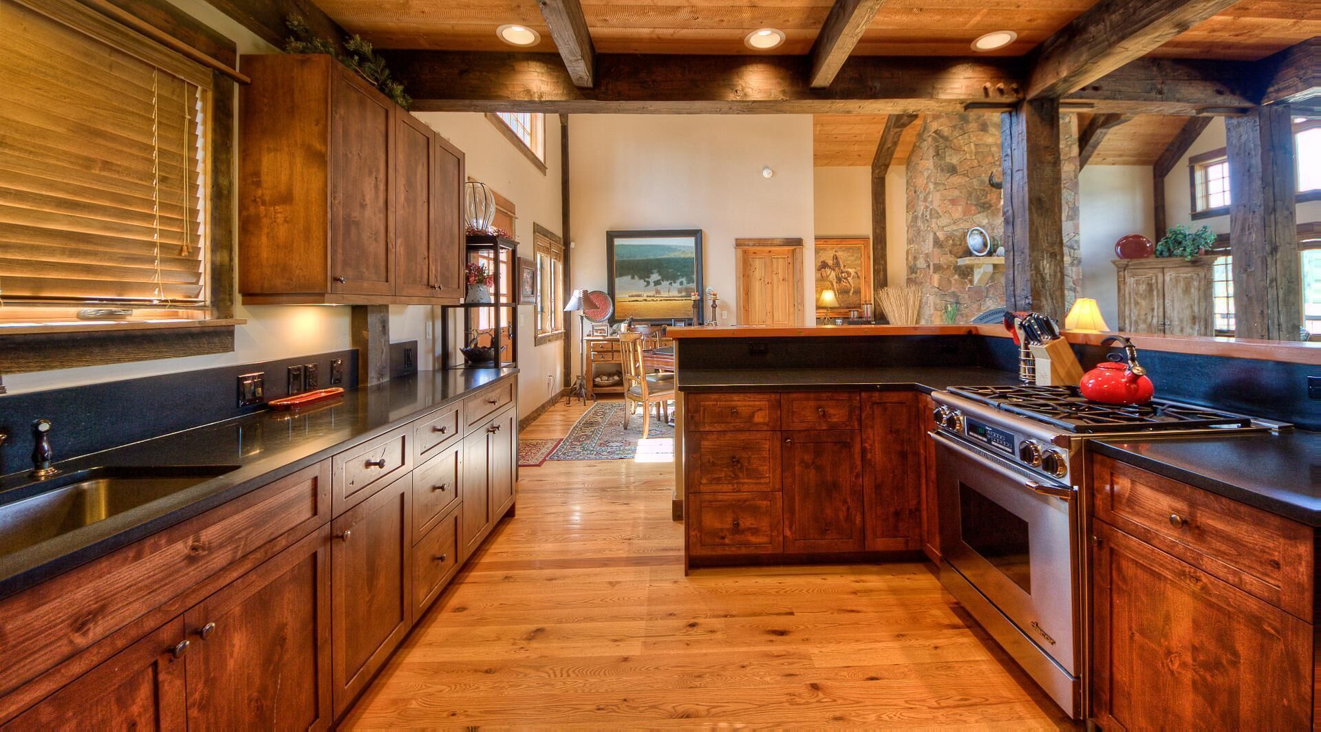 A kitchen with wooden cabinets, a stove, and a red kettle.