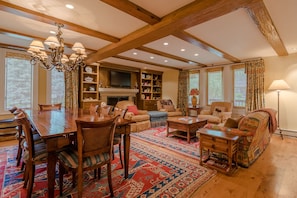 Cozy living space with a high ceiling, dining table, sofa, and fireplace.