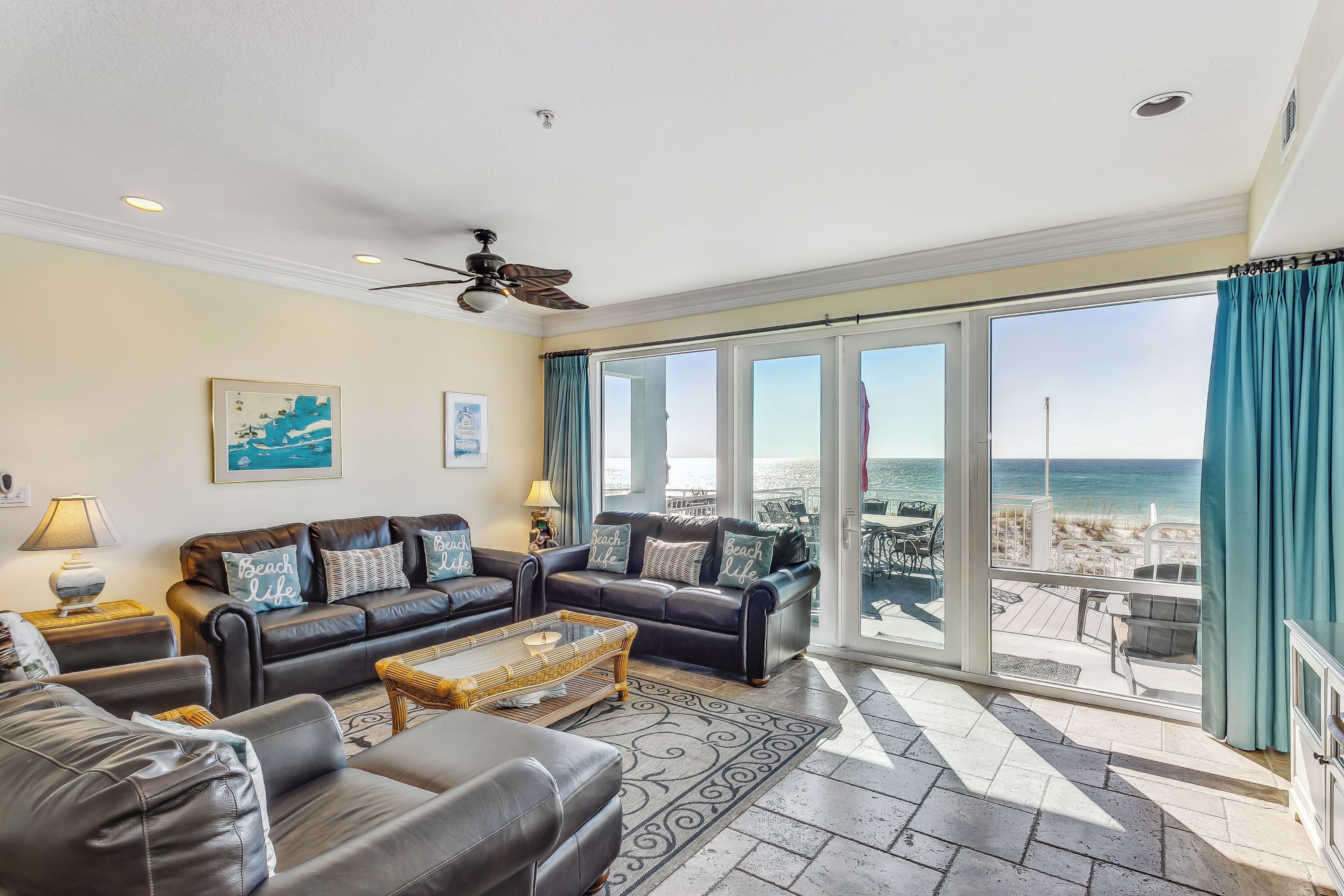 A spacious living room with a large sliding glass door leading to a balcony with a view of the beach.