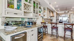 Una cocina con muebles blancos, encimera de granito y horno empotrado.