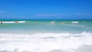 A beach with clear turquoise water and waves. - Sandy Shores • Steps to Beach & Frenchy's • Pet Friendly • Patio ➠ 20 Kendall 1 (Clearwater)