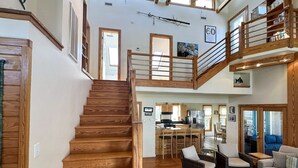 A spacious interior with a wooden staircase, a kitchen area, and a living room with seating.