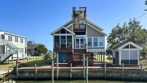 A two-story house with a balcony, a small dock, and a pond in front.