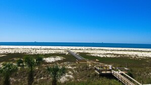 Ein Strand mit einer Holzpromenade, die zu einem sandigen Bereich mit Palmen führt.