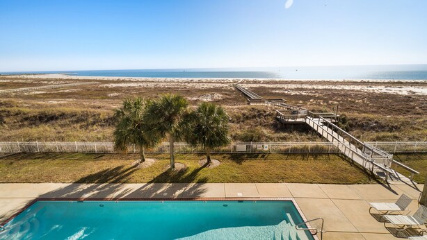 Ein Pool mit Blick auf den Strand und einer Holzterrasse.