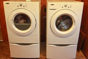 Two stacked front-loading washing machines in a room with wooden flooring. - The Cottage is on 450 acres w/hot tub, Private 4wheeler trails (Hatfield)