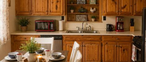 A kitchen with wooden cabinets, a dining table with chairs, a ceiling fan, and a sign that reads 'KITCHEN'.