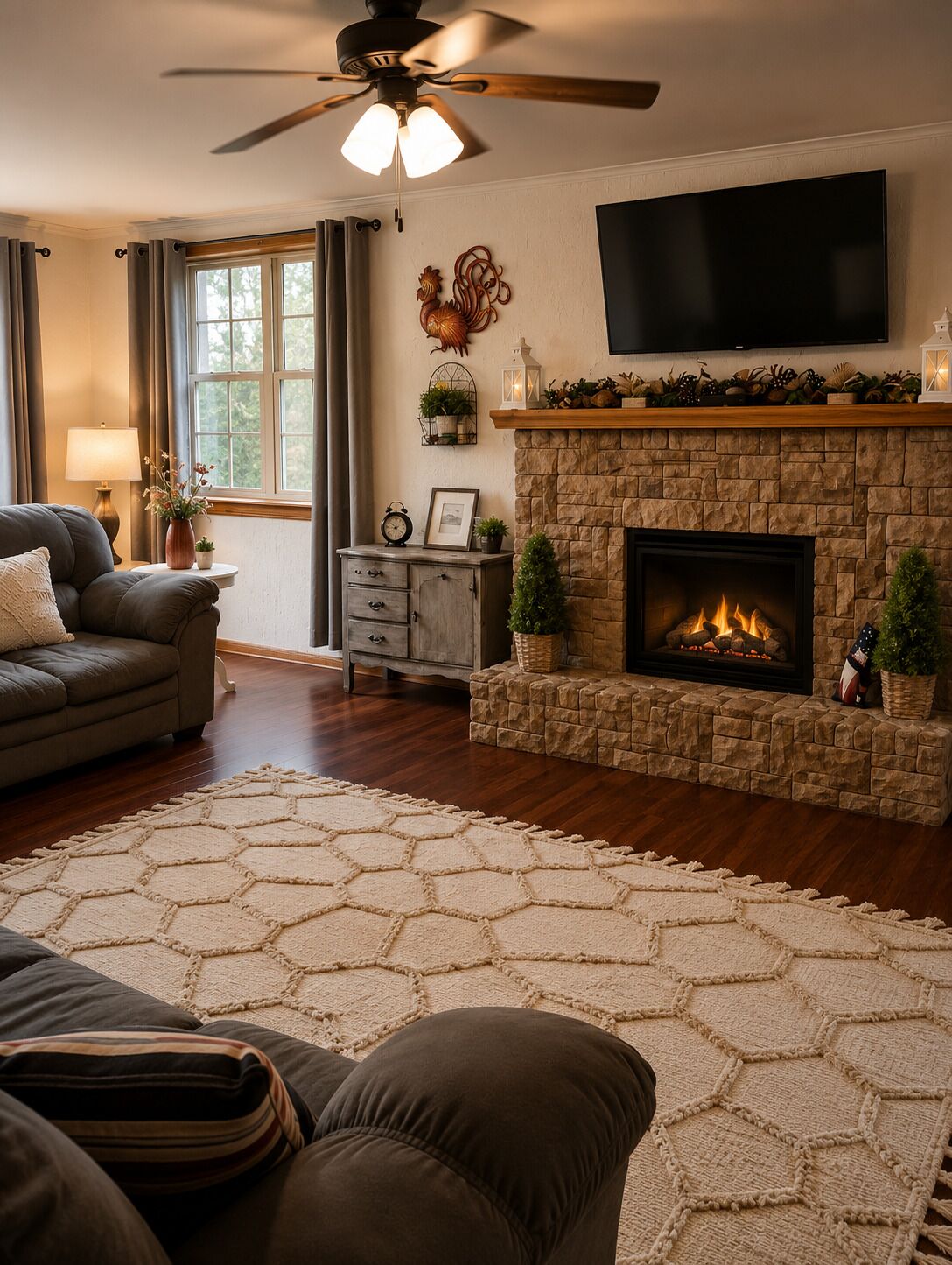 A living room with a fireplace, a television mounted above it, and a ceiling fan.