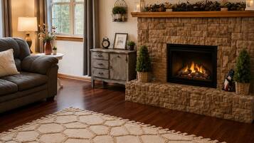 A living room with a fireplace, a television mounted above it, and a ceiling fan.