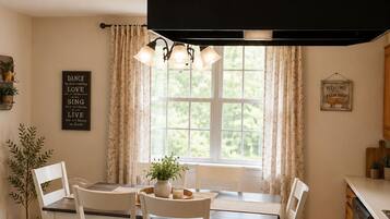 A kitchen with wooden cabinets, a dining table with chairs, a bench, and a window with curtains.