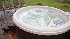 A hot tub on a wooden deck with chairs and a grassy background. - The Cottage is on 450 acres w/hot tub, Private 4wheeler trails (Hatfield)