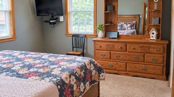 Une chambre à coucher comprenant un lit, une commode, un téléviseur et un ventilateur de plafond.