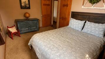 Un dormitorio con una cama, un aparador, una silla, un ventilador de techo y una puerta.