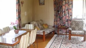 Una sala de estar con un sofá, una mesa de comedor con sillas y una alfombra estampada.
