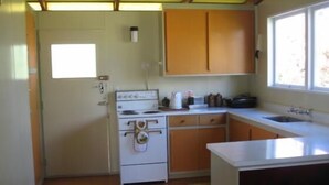 Una cocina pequeña con armarios de madera, una estufa blanca y un ventanal que proporciona luz natural.