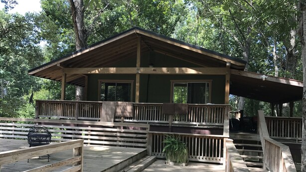 Eine Holzhütte mit Balkon, überdachter Terrasse und kleinem Garten.
