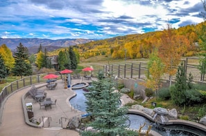 A patio area with outdoor seating, a small pool, and a view of autumn foliage and mountains.