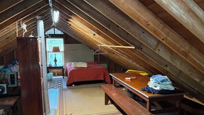 A cozy attic bedroom with a sloped ceiling, a wooden bench, a table, a bed, and a desk with a lamp. - Summer family cabin on Lake Ontario, Pulaski
NEWLY UPDATED!! (Pulaski)