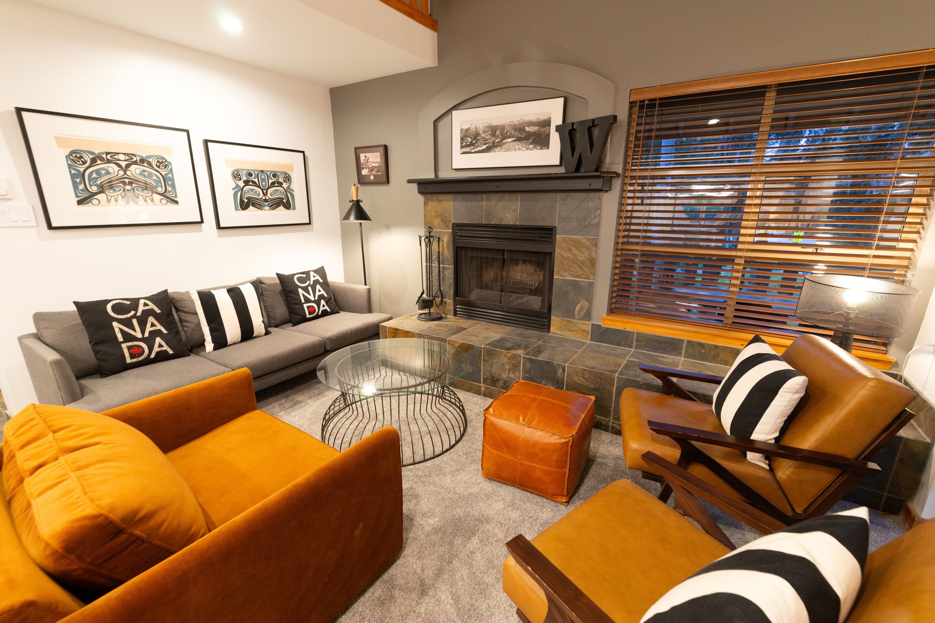 A modern living room with a fireplace, a glass coffee table, and a sofa with decorative pillows.