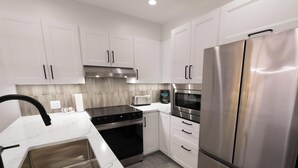 A modern kitchen with white cabinets, stainless steel appliances, a built-in oven, and a microwave. - Forest Trails - Easy Ski Access, Private Garage, Free Village Shuttle (Whistler)