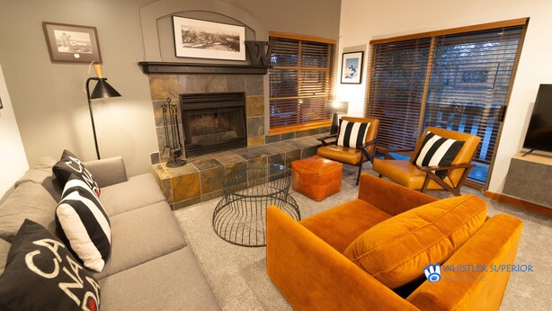 Een moderne woonkamer met een open haard, comfortabele zitplaatsen en een televisie.