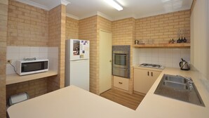 Eine kleine Küche mit Mikrowelle, Kühlschrank, Backofen und Spüle.