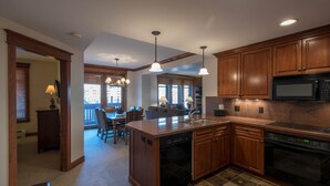 A kitchen with wooden cabinets, a dishwasher, a microwave, and a dining area with a table and chairs.