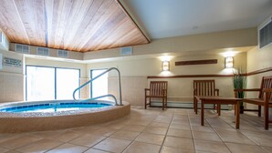 A pool area with a wooden ceiling, tiled floor, and a seating area with chairs and a table.